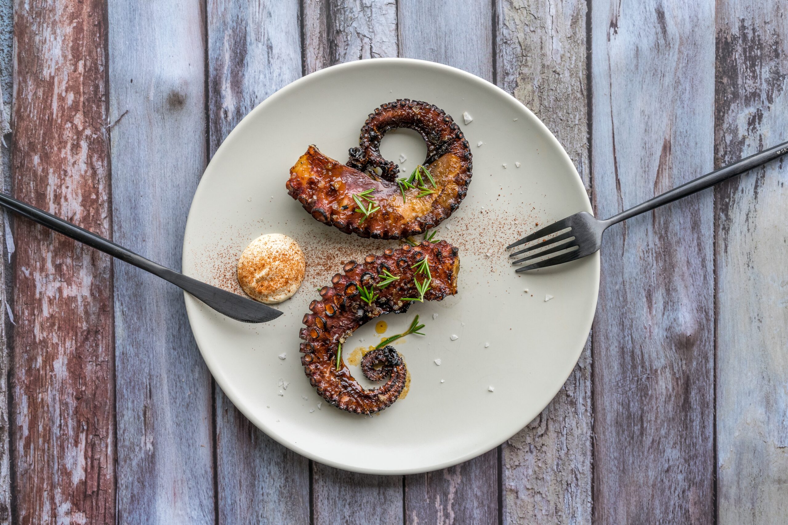 https://foodiemag.co.za/wp-content/uploads/2023/06/horizontal-shot-dish-with-octopus-arms-with-spices-white-plate-with-silverware-scaled.jpg